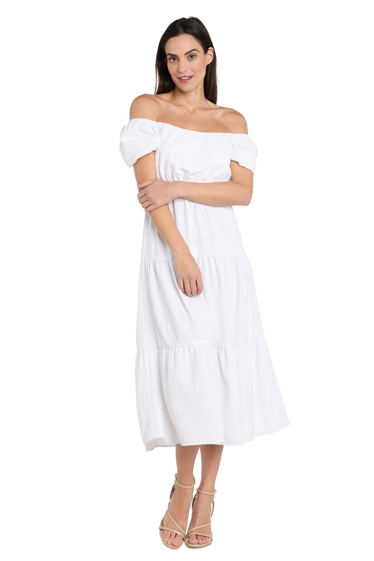 Woman wearing the Tea-Length White Party Dress: R&M Richards 6669 with off-the-shoulder neckline and short sleeves, paired with beige strappy heels, standing against a plain white background.